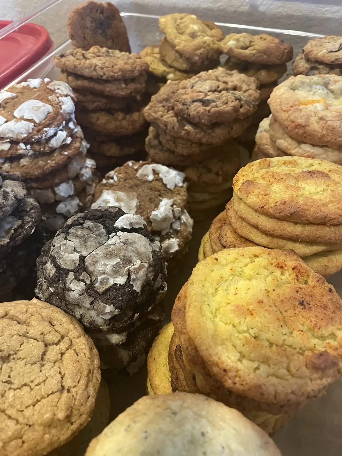A pile of cookies, some dark, some golden, stacked in a tray.