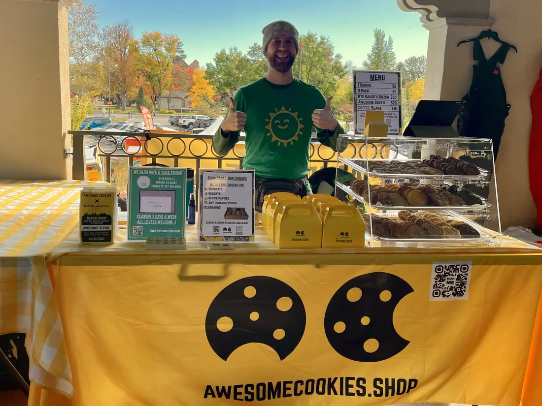 The maker behind a yellow checked table of boxed cookies.