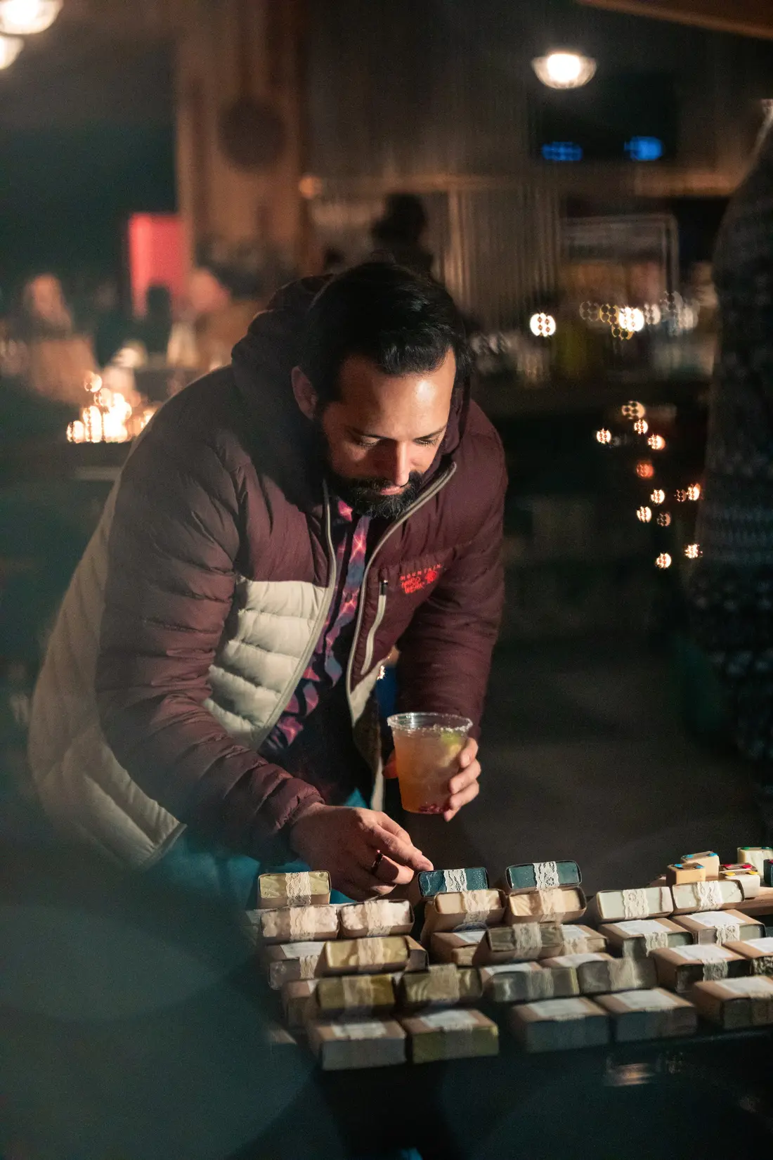 A maker lighting a candle on a dark table at the RiNo Holiday BAZAAR.