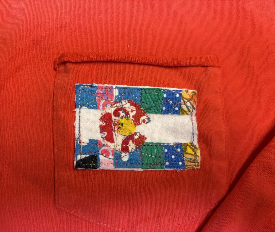 A patchwork Colorado flag sewn onto the pocket of a red shirt.