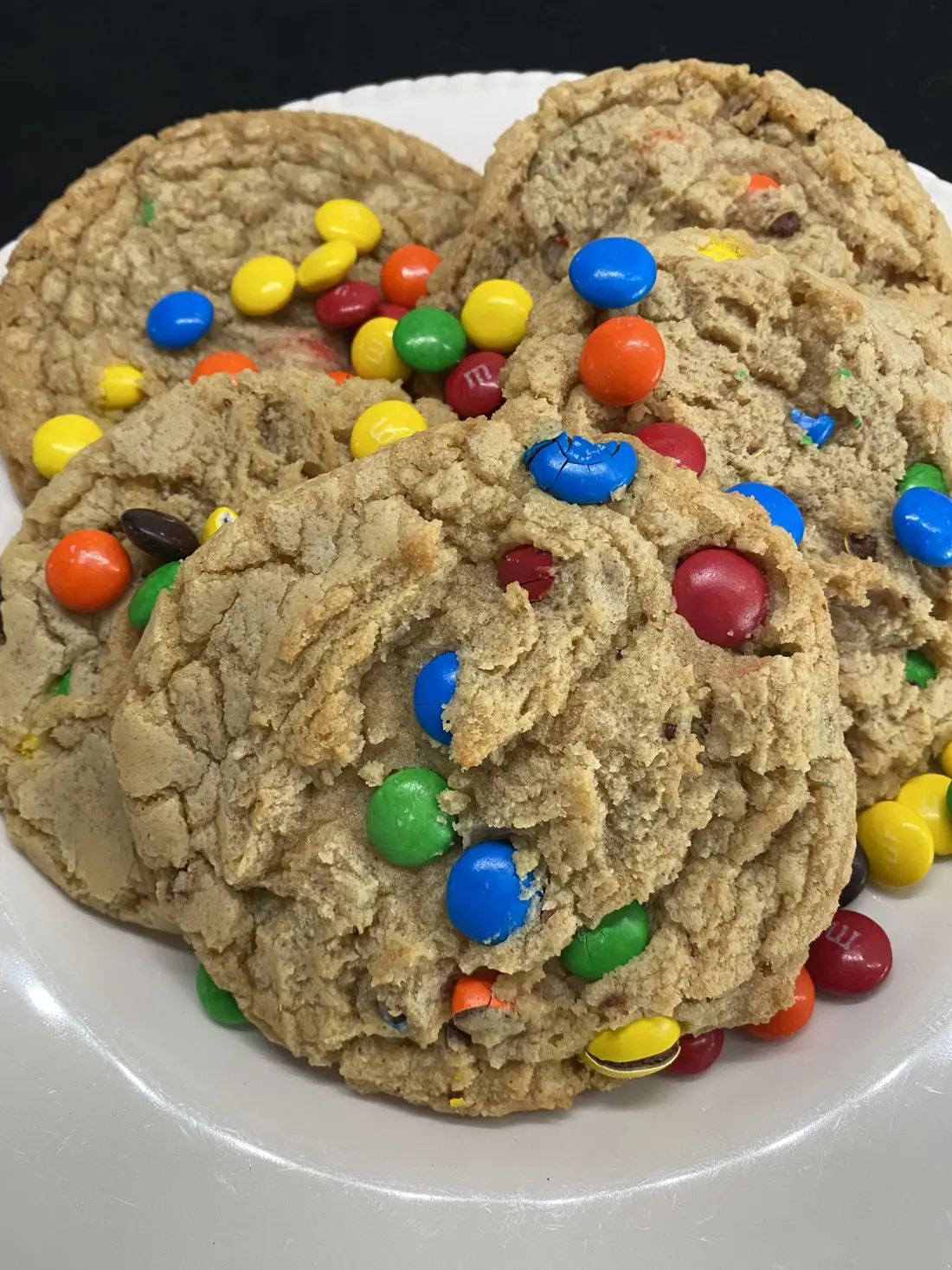 Two large cookies studded with candy-coated chocolates on a white plate.