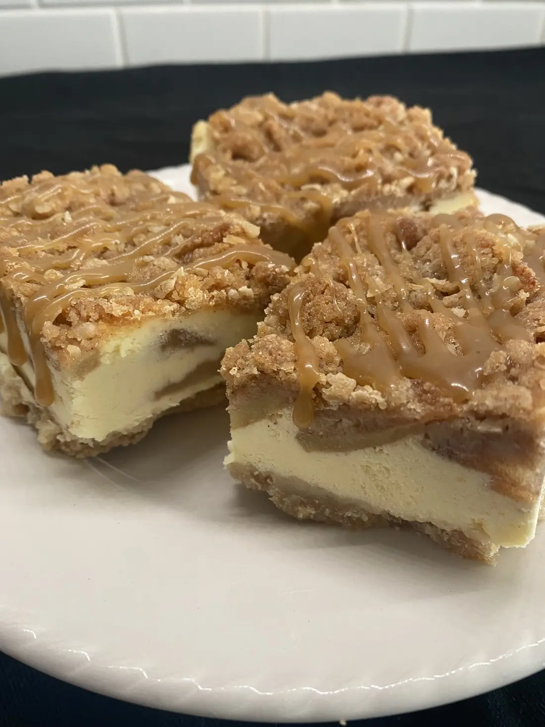 Squares of cheesecake with a caramel crumble top on a plate.