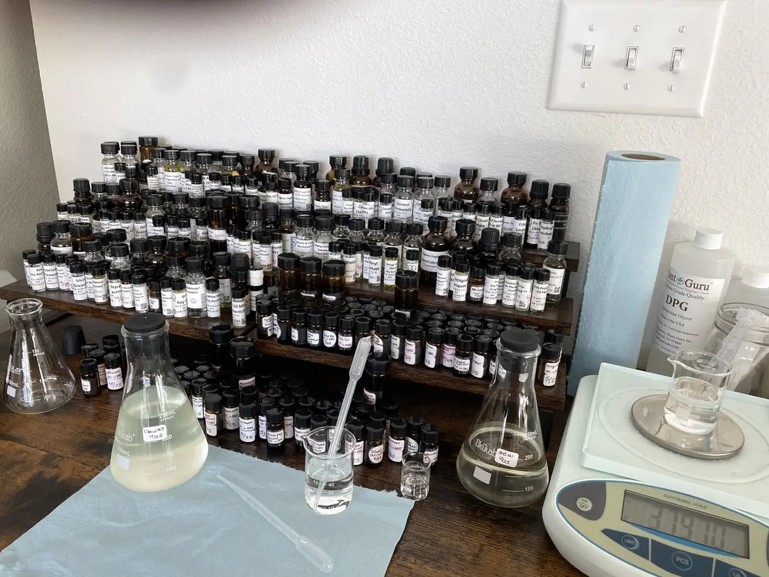 Rows of small amber bottles, beakers and a scale on a work table.