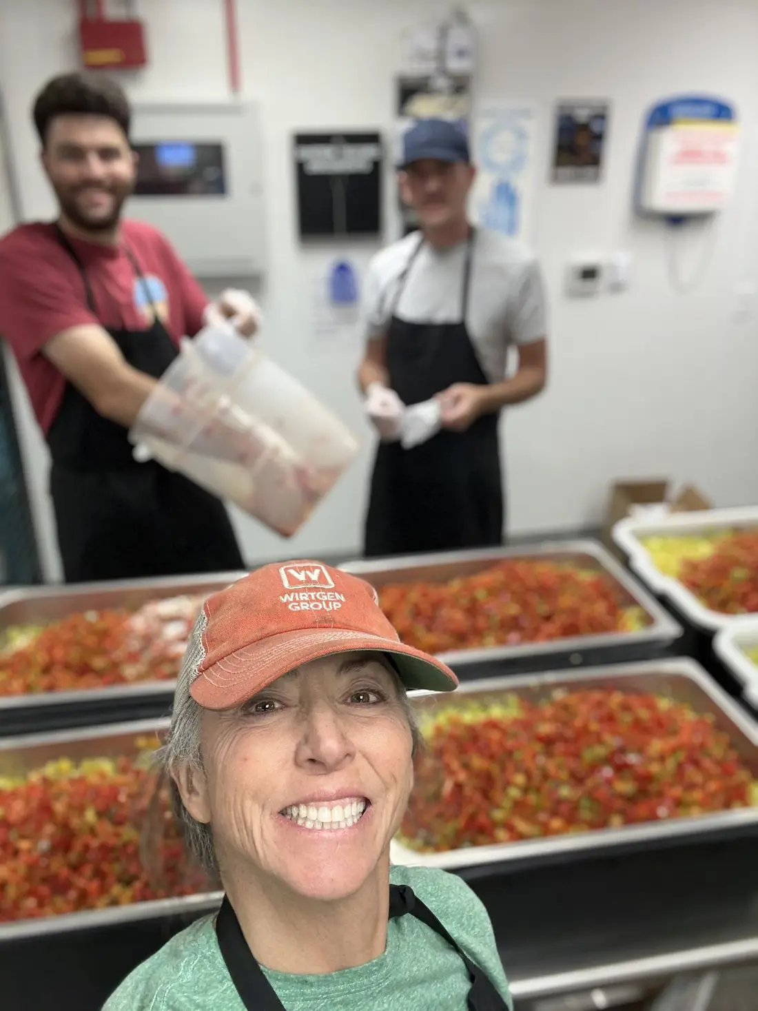 The makers in a kitchen with trays of chopped peppers.