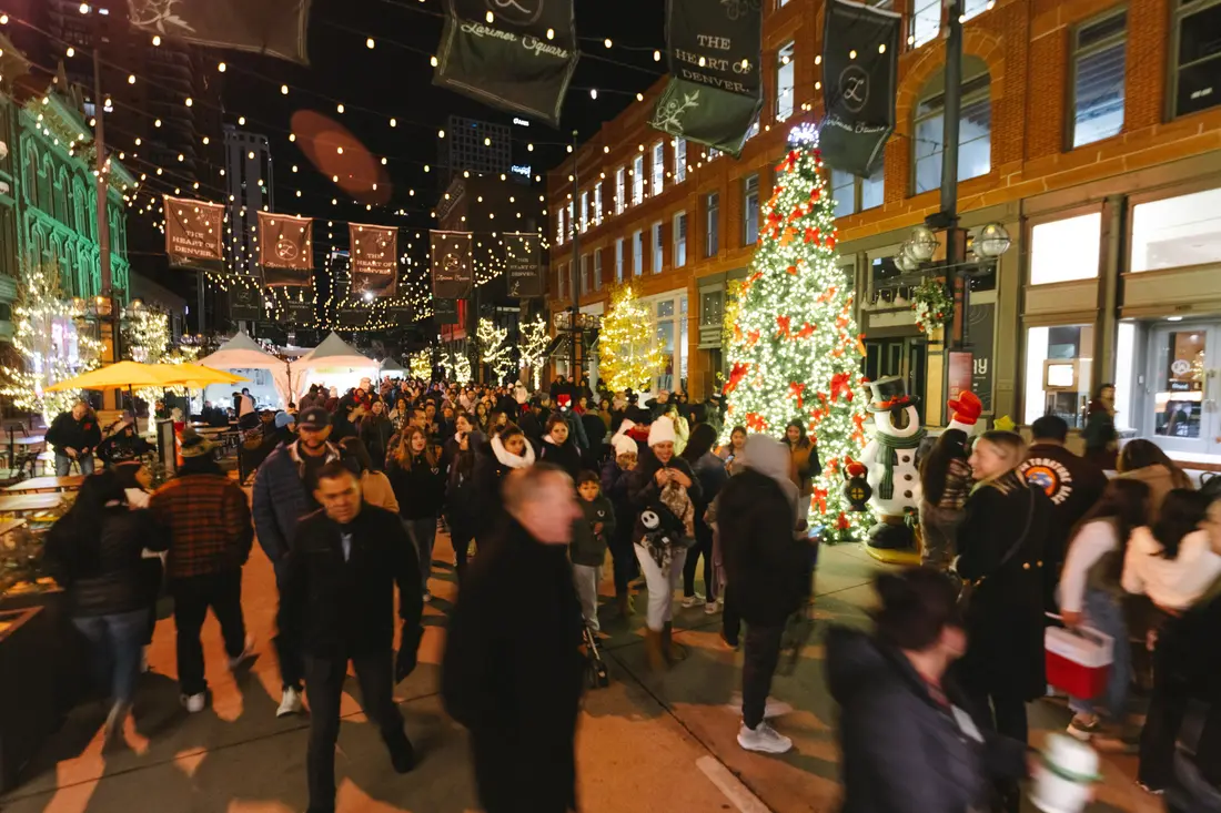 A Holiday BAZAAR at night: the crowd on Larimer Square under the string lights, the tree lit behind them.