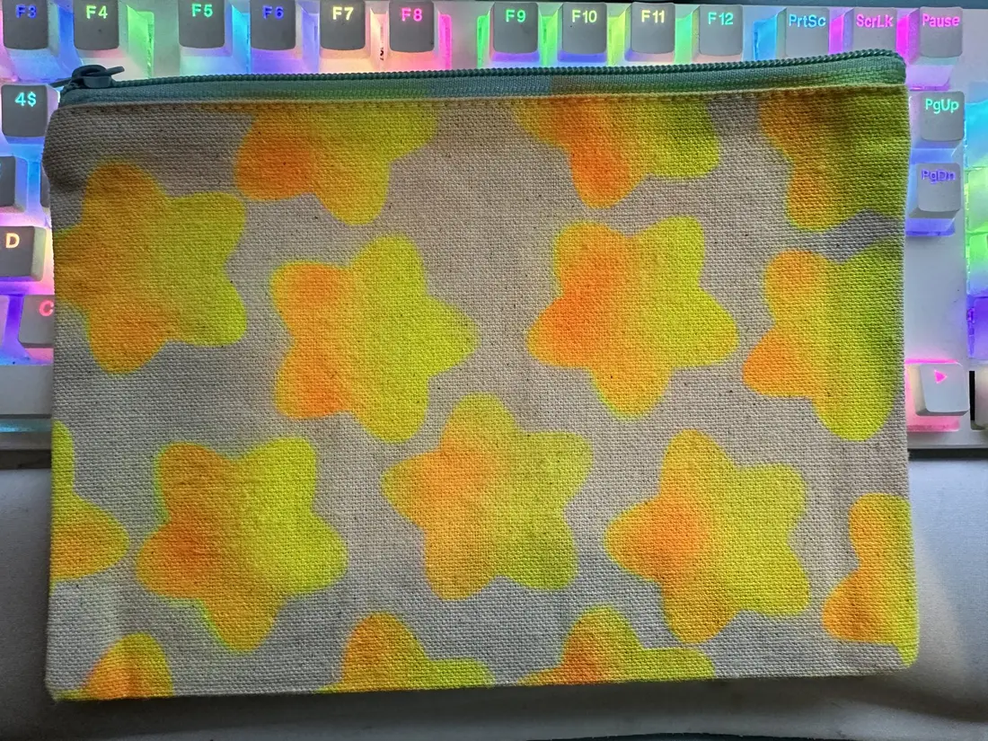 A zip pouch airbrushed in orange and yellow checks over a holographic ground.