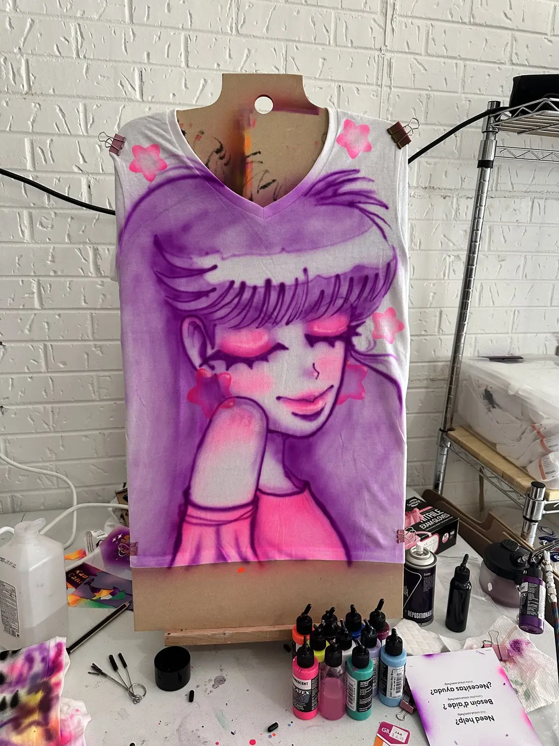 An airbrushed portrait of a girl with large eyes in pinks and purples on a canvas bag.