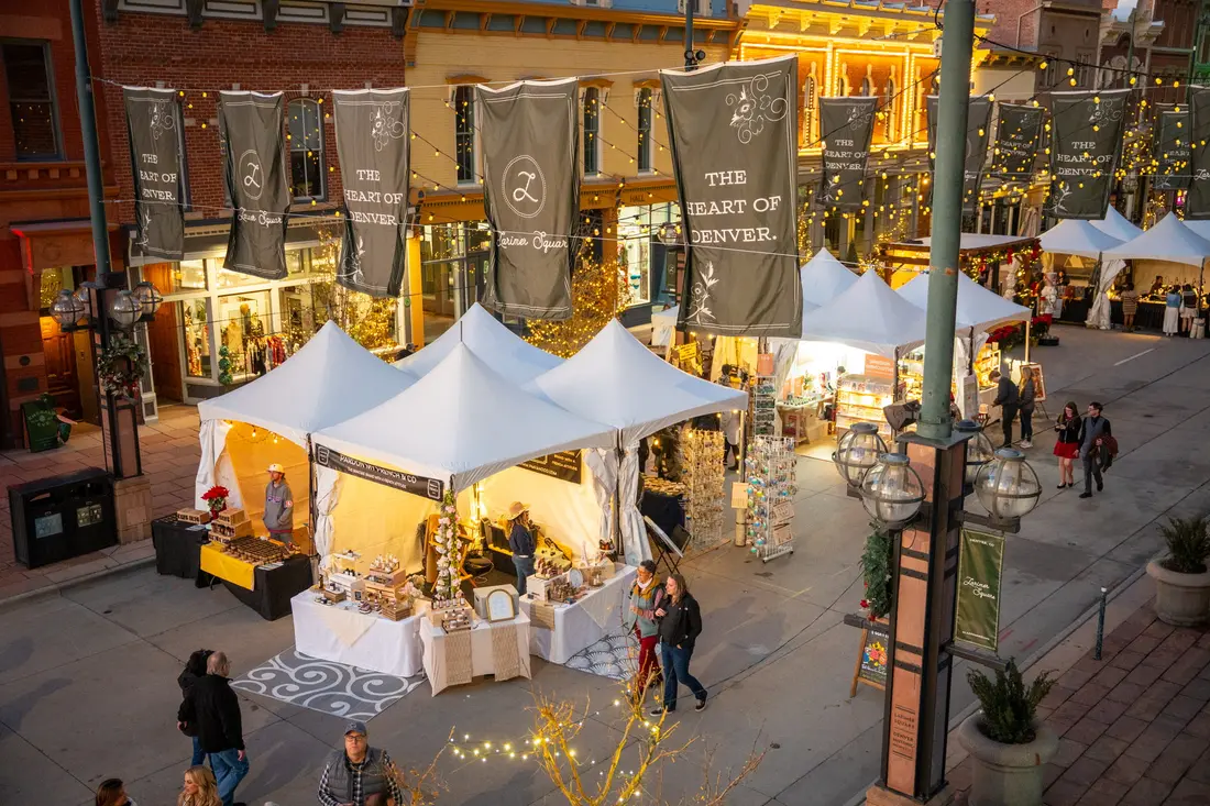 Larimer Square at dusk: the tents lit from inside under the banners and string lights, the block filling up.