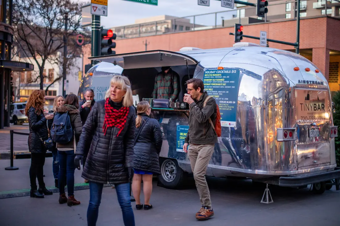 The crowd in winter coats at the trailer bar on a market afternoon.