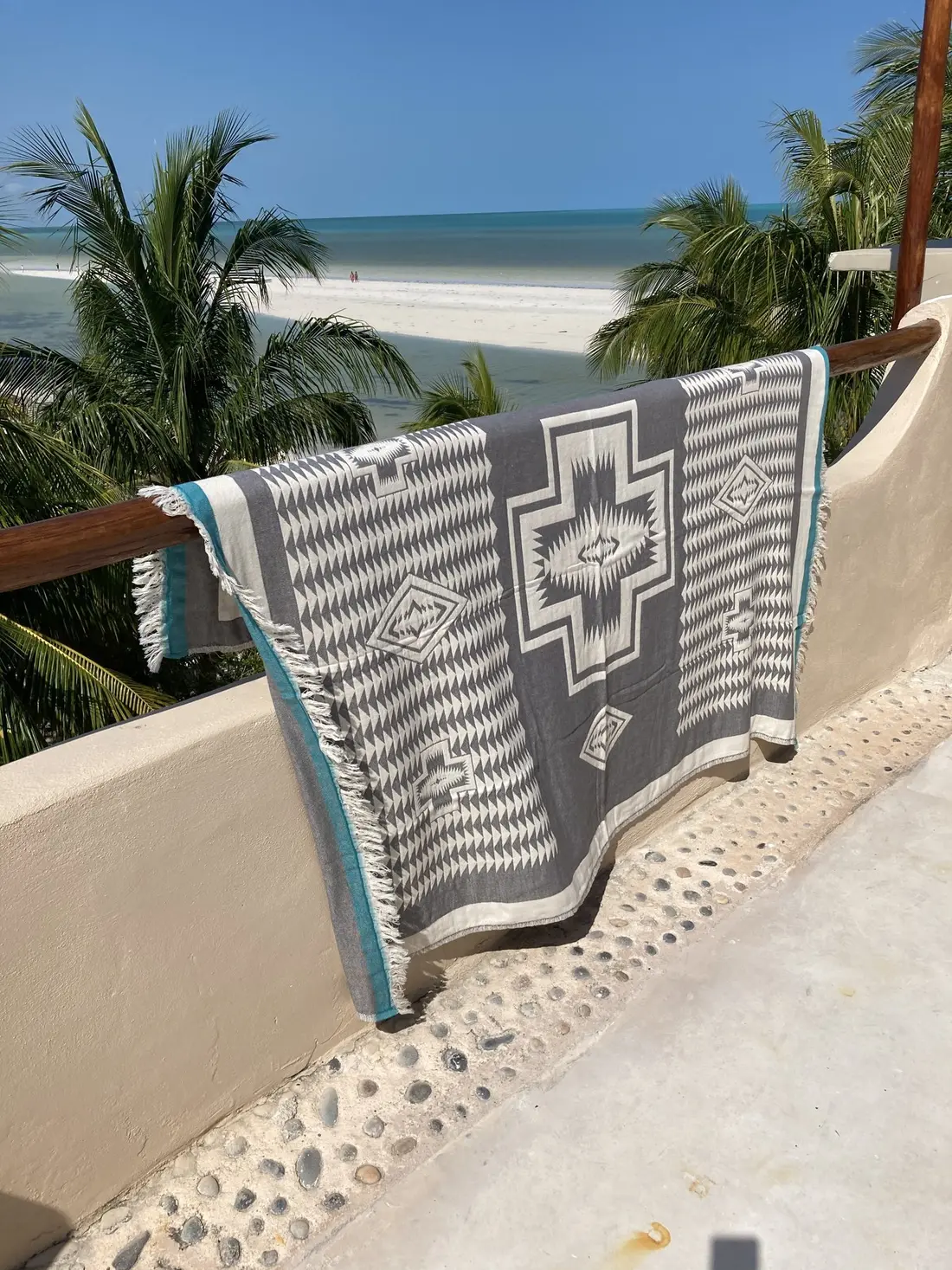 A gray and white Turkish towel hung over a balcony rail above the sea.