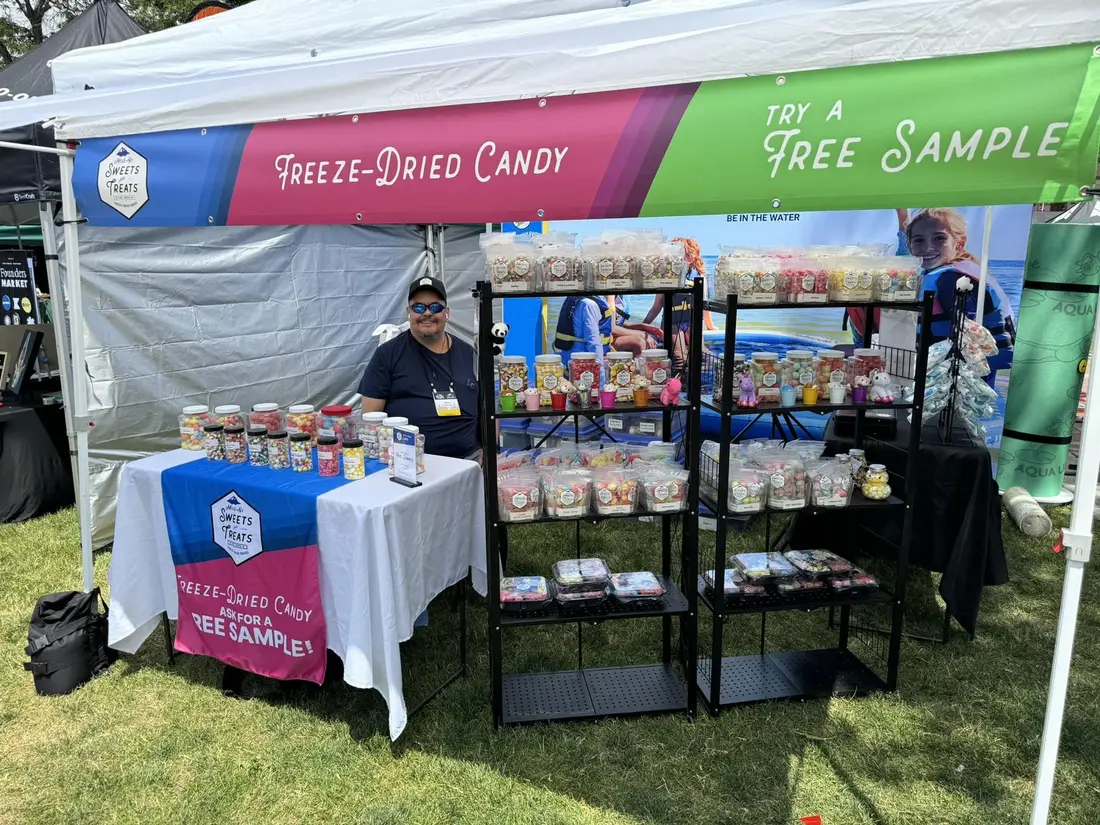 The maker under a white tent with a rack of freeze-dried candy and a Try a Free Sample sign.
