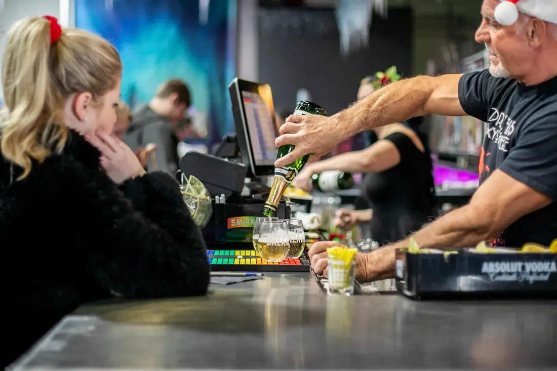 A bartender pouring a drink into a Denver BAZAAR glass, December 2020.