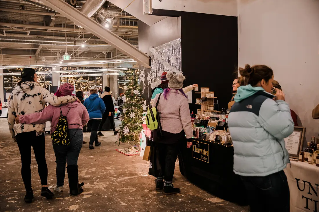 Shoppers in winter coats between booths at the Downtown Lakewood Holiday BAZAAR, November 2022.