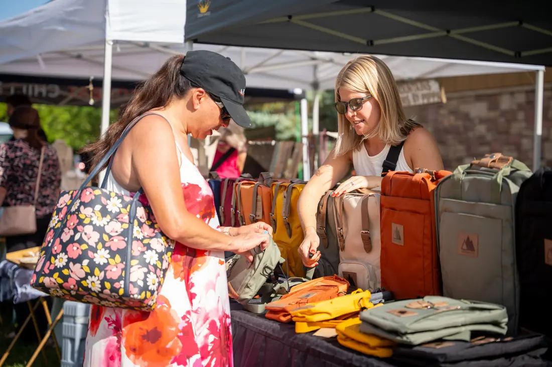 A shopper going through a table of goods at a Saturday Night BAZAAR in Aspen Grove.