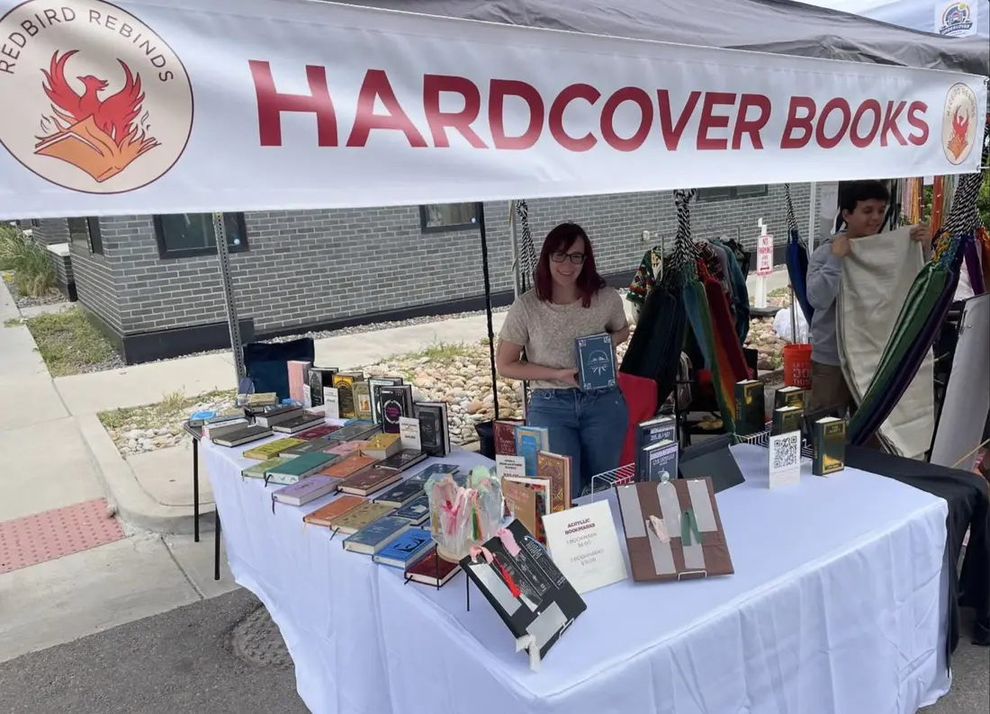 The maker under a white tent with a table of rebound hardcovers and a sign reading Hardcover Books.