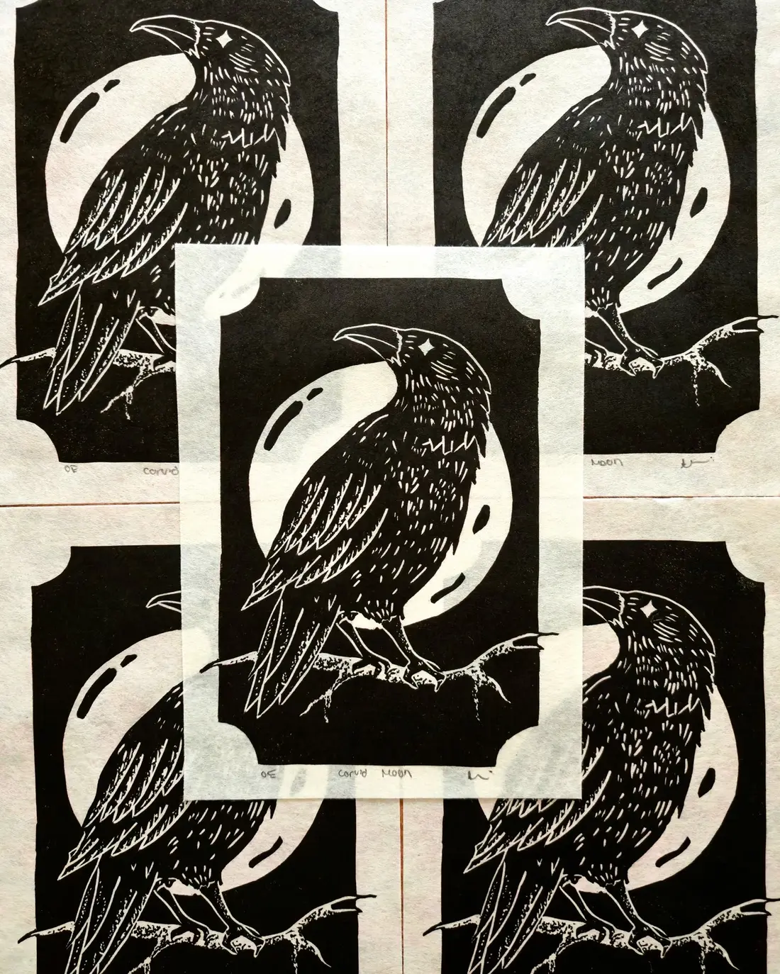 Black and white block prints of a crow, laid in a grid with one framed in the center.