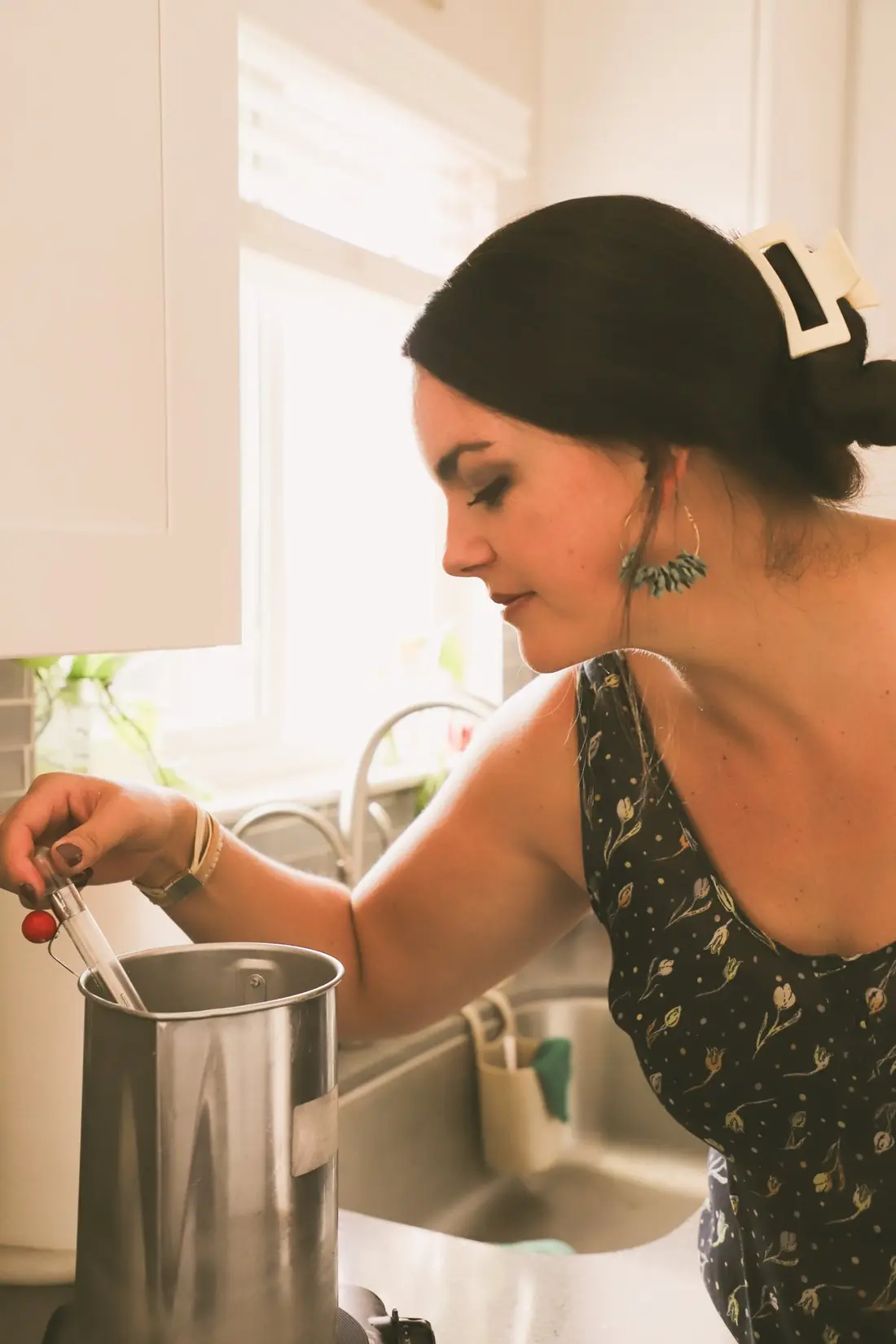 The maker pouring wax into a candle jar at a kitchen counter.